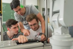 Lehrer und Schüler arbeiten an einem Technikprojekt.