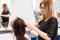 Eine Auszubildende im Friseurhandwerk macht ihrer Mitschülerin die Haare.