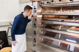 Azubi im Bäckerbereich schaut in den Ofen, der mit Plätzchen gefüllt ist