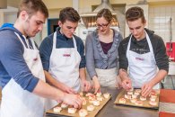 Eine Lehrerin und drei Schüler bereiten Fingerfood zu.