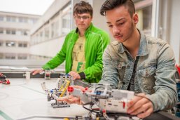 Das Bild zeigt zwei Schüler, die mit Lego-Elektrotechnik arbeiten.