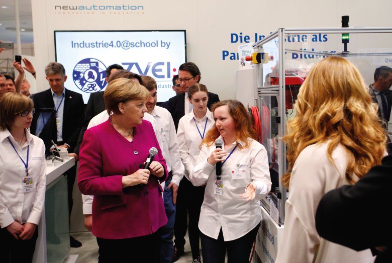 Bild der Hannover Messe 2018; zu sehen ist Frau Merkel, wie sie mit einer Schülerin spricht, die ihr eine technische Anlage vorstellt