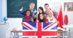 eine Gruppe von Schülern stehen im Klassenraum und halten die Flagge von Großbritannien hoch.