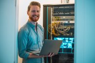 Male Caucasian IT technician using laptop in server room Motivierter IT-ler benutzt einen Laptop im Serverraum