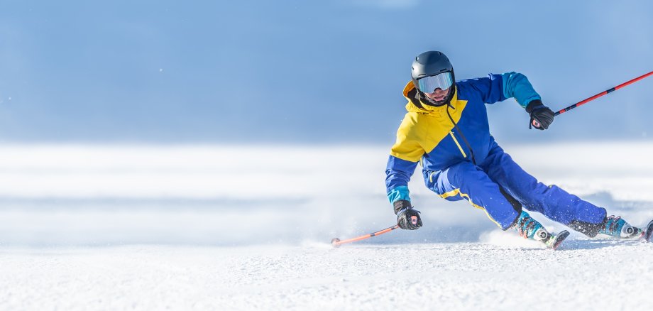 A young aggressive skier on an alpine slope demonstrates an extreme carving skiing style. He is skiing on morning perfectly groomed piste. A young aggressive skier on an alpine slope demonstrates an extreme carving skiing style. He is skiing on morning perfectly groomed piste.
